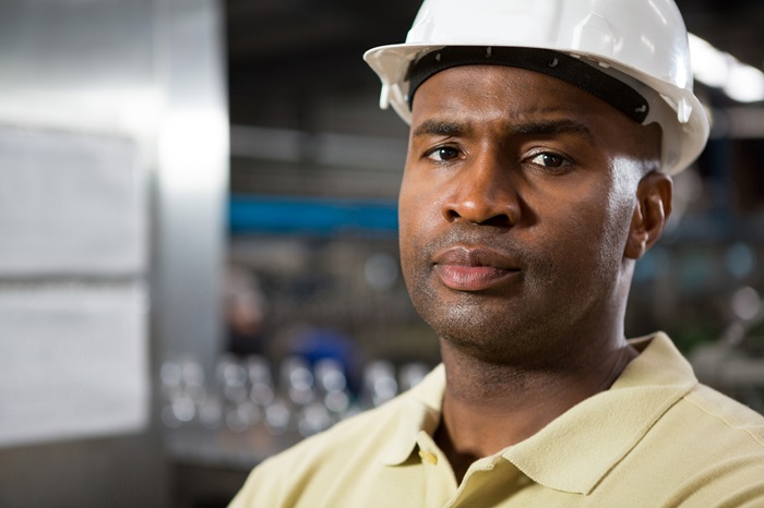 Close up of portrait serious male employee wearing hard hat in factory